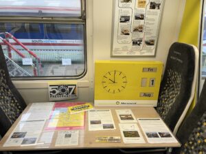 Display of Merseyrail ephemera including booklets, pocket timetables and old maps. Also prominently displayed is a clock from a Merseyrail booking office