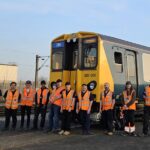 Class 507 Preservation Society volunteers pose in front of 507001 in Litchurch Lane works, Derby